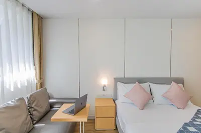 a bedroom with a bed and a laptop on a table at United Residence Ekamai Bangkok in Bangkok