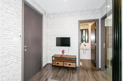 a living room with a tv and a wooden table at The Base Park East - Bangkok Sukhumvit 77 in Bangkok