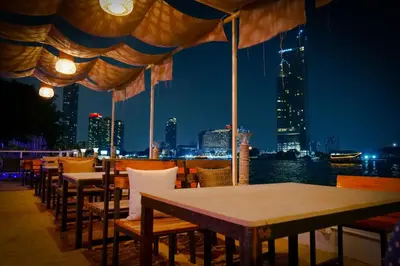 a restaurant with tables and chairs with a view of the city at Anandpura Riverside Hotel in Bangkok