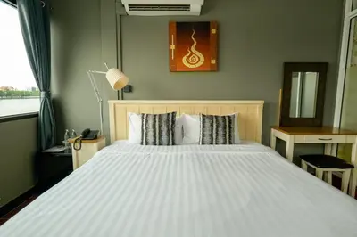 a bedroom with a large white bed and a window at Anandpura Riverside Hotel in Bangkok