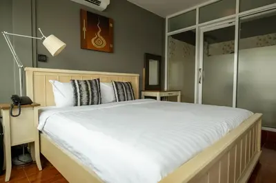a bedroom with a large bed with white sheets at Anandpura Riverside Hotel in Bangkok