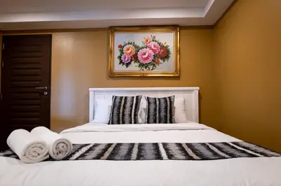 a bedroom with a white bed with a picture on the wall at Anandpura Riverside Hotel in Bangkok