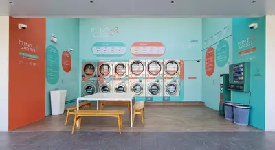 a room with a table and chairs and washing machines at Mintel Huamark in Bangkok