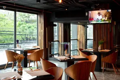 a restaurant with tables and chairs and a flat screen tv at RakYim Siam - Sukhumvit 15 in Bangkok