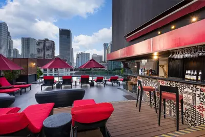 a rooftop bar with red chairs and tables on a building at RakYim Siam - Sukhumvit 15 in Bangkok