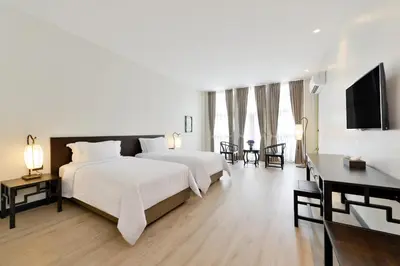 a bedroom with a large white bed and a television at Oldthaiheng Hotel in Bangkok