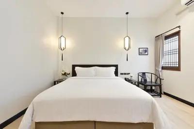 a bedroom with a large white bed and a chair at Oldthaiheng Hotel in Bangkok