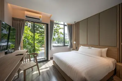 a bedroom with a bed and a desk and a television at SHAN Villas Sukhumvit ฌานวิลล่า สุขุมวิท in Bangkok