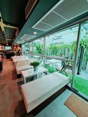 a living room with couches and tables and windows at The Key Point Hotel in Bangkok