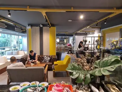 a living room with a person sitting at a table at The Key Point Hotel in Bangkok