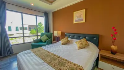 a bedroom with a bed and a chair and a window at Plearnwan Deluxe Mansion in Bangkok