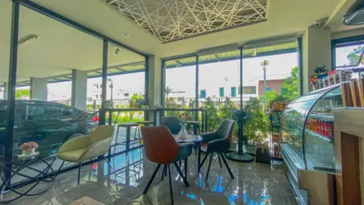 a restaurant with chairs and a table and windows at Plearnwan Deluxe Mansion in Bangkok