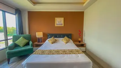 a bedroom with a bed and a green chair at Plearnwan Deluxe Mansion in Bangkok