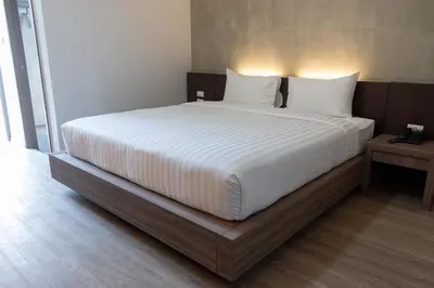 a bed with white sheets and pillows in a room at โรงแรมดับเบิ้ลดี ปากเกร็ด Double D hotel in Pak Kret