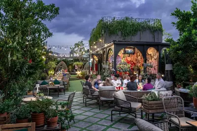 a group of people sitting at an outdoor restaurant at The Quartier Hotel Phromphong - Thonglor in Bangkok