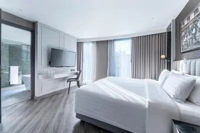 a bedroom with a bed and a desk and a television at The Quartier Hotel Phromphong - Thonglor in Bangkok