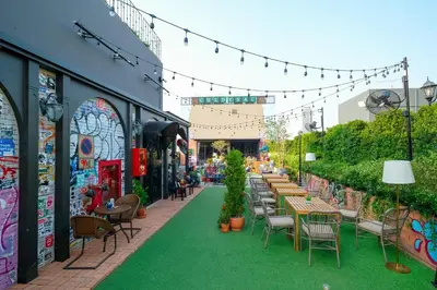a patio with tables and chairs on a green lawn at The Quartier Hotel Phromphong - Thonglor in Bangkok