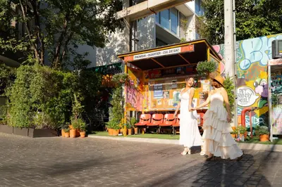 two women in white dresses standing in front of a building at The Quartier Hotel Phromphong - Thonglor in Bangkok