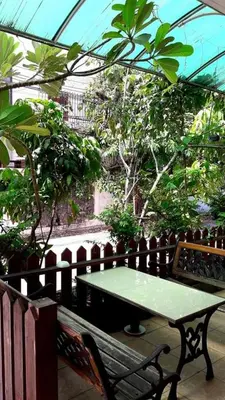 a green table and a bench in a greenhouse at Jirapong apartment in Bangkok