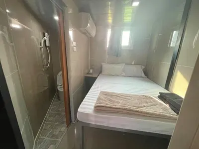 a small room with a bed and a shower at Charinsup Pinklao Hotel in Bang Kruai