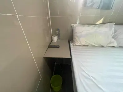 a small room with a bed and a desk with a pillow at Charinsup Pinklao Hotel in Bang Kruai
