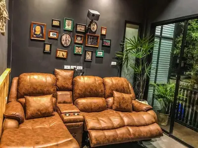 a living room with a brown leather couch at Exclusive access to the whole garden. in Bangkok