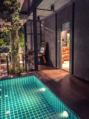 a swimming pool in front of a house at Exclusive access to the whole garden. in Bangkok