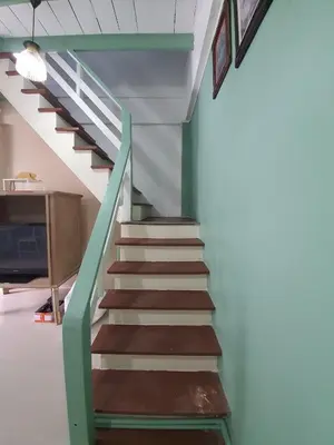 a staircase in a house with a green and brown railing at บ้านอรุณHome in Bangkok