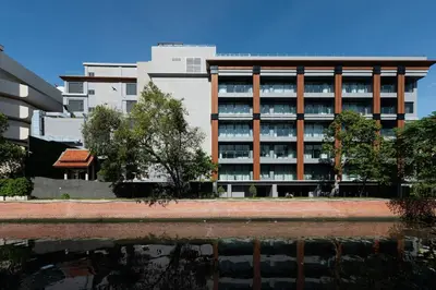 a building with a reflection in a body of water at Ayathorn Bangkok in Bangkok