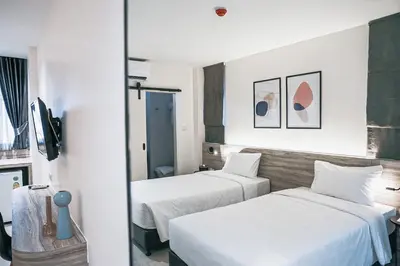 two beds in a room with white walls at HOMITEL Bangkok in Bangkok