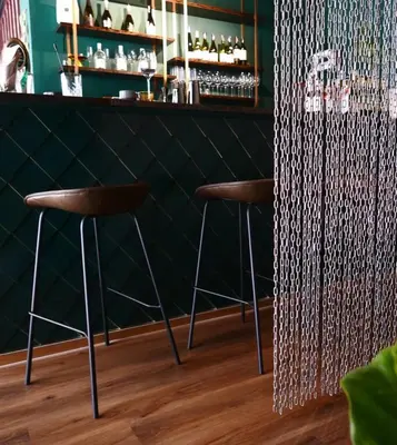 a bar with two stools in front of a green wall at HOMITEL Bangkok in Bangkok