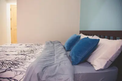 a bed with blue and white pillows on it at Baan Romdee in Nonthaburi