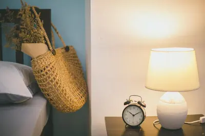 a table with a lamp and a purse and a clock at Baan Romdee in Nonthaburi