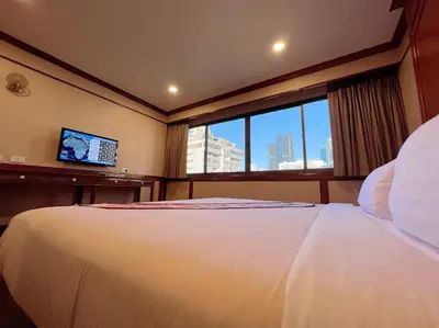 a bedroom with a large white bed and a window at The Promenade Bangkok in Bangkok