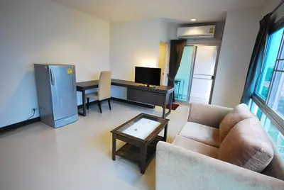 a living room with a couch and a desk with a television at Baan Mina in Bangkok