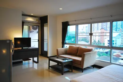 a hotel room with a bed and a chair and a television at Baan Mina in Bangkok