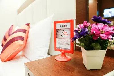 a table with a sign and a vase of flowers at Studio Nana by iCheck inn in Bangkok