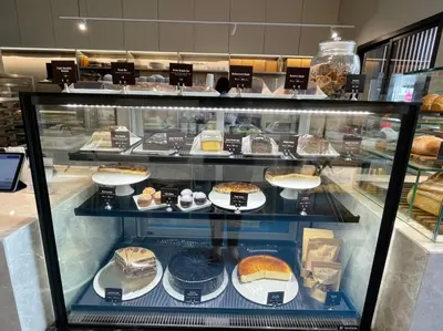 a display case in a bakery with cakes and pastries at The Quart Ruamrudee by UHG in Bangkok