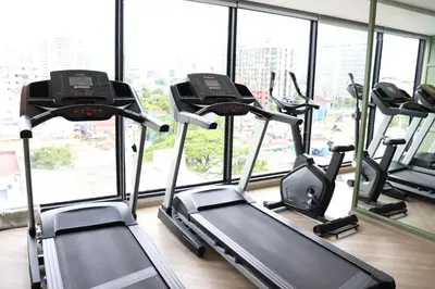 a gym with several tread machines in front of a window at The Quart Ruamrudee by UHG in Bangkok
