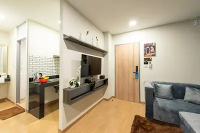 a living room with a blue couch and a kitchen at Metro Hotel Ratchada 36 in Bangkok