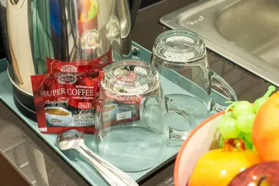 a counter with a tray of food and a plate of fruit at Metro Hotel Ratchada 36 in Bangkok