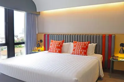 a bedroom with a large white bed with orange pillows at The Quarter Onnut by UHG in Bangkok