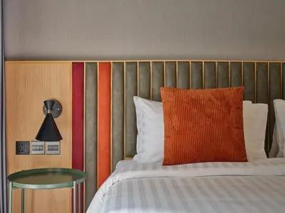 a bed with an orange pillow and a glass table at The Quarter Onnut by UHG in Bangkok