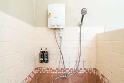 a shower in a bathroom with a shower head at The Palm Hotel in Salaya