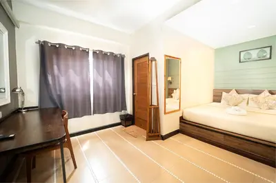 a bedroom with a bed and a desk and a table at The Palm Hotel in Salaya