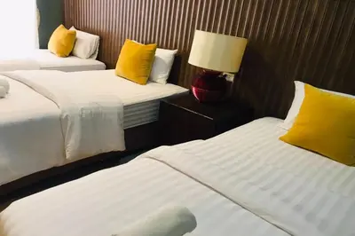 a hotel room with two beds with yellow pillows at The Palm Hotel in Salaya