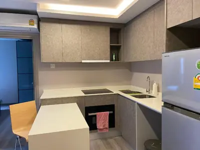a small kitchen with a stove and a refrigerator at Politan Breeze, Chaophraya River view in Ban Sai Ma