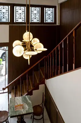 a chandelier hanging from a staircase with a table and chairs at Loftel 22 Hostel in Bangkok