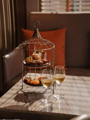 a plate of pastries and two glasses of wine on a table at Aira Hotel Bangkok Sukhumvit 11 in Bangkok