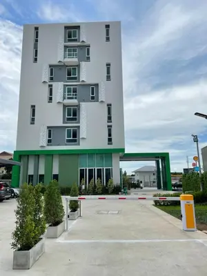 a tall white building with a parking lot at Sabai Residence @Bangyai in Nonthaburi